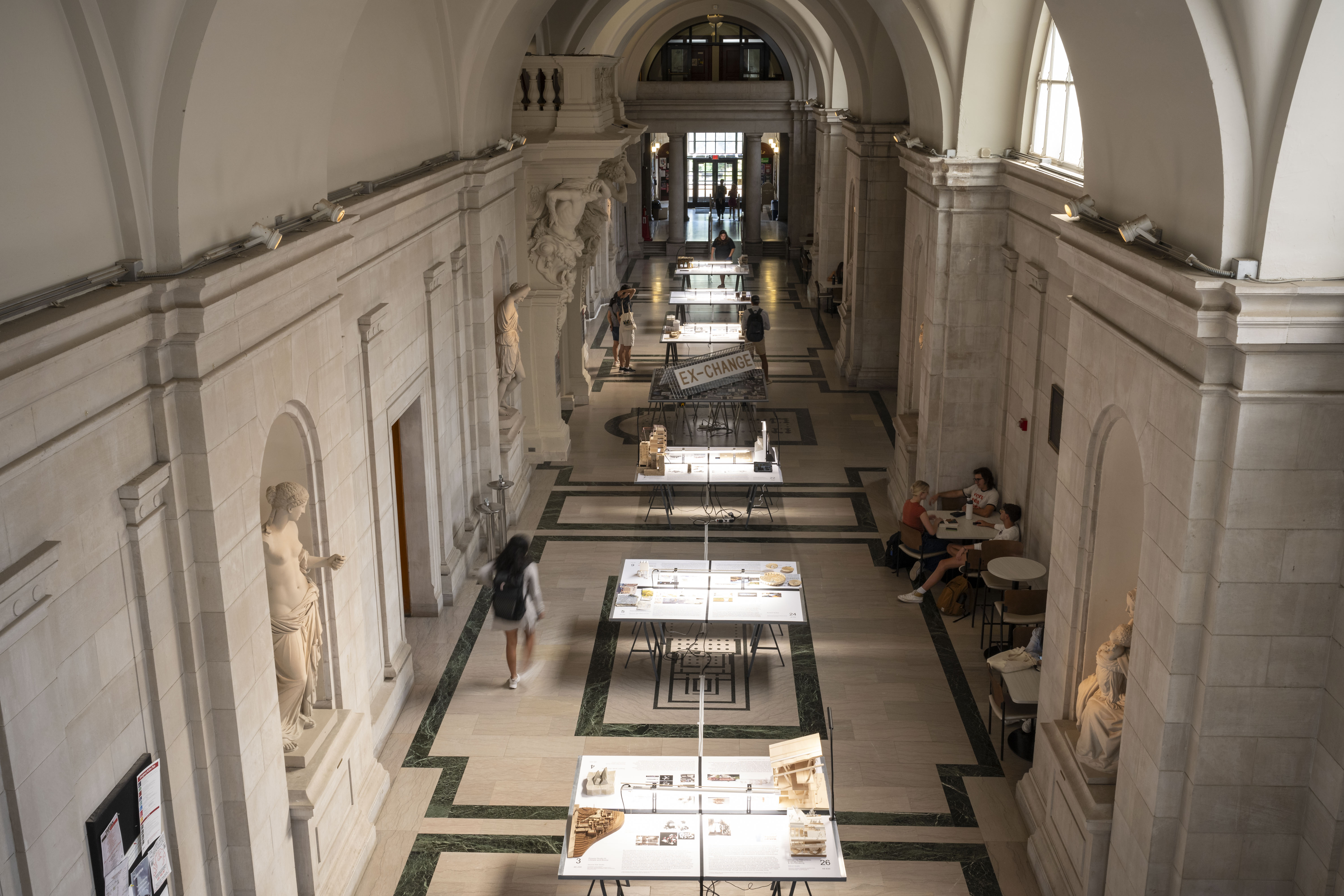 Overhead image of the EX-CHANGE Exhibition showing tables with student work from CM-A studios and courses.