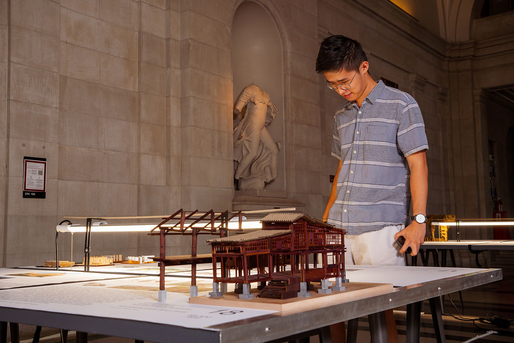 A passer-by admires student models.