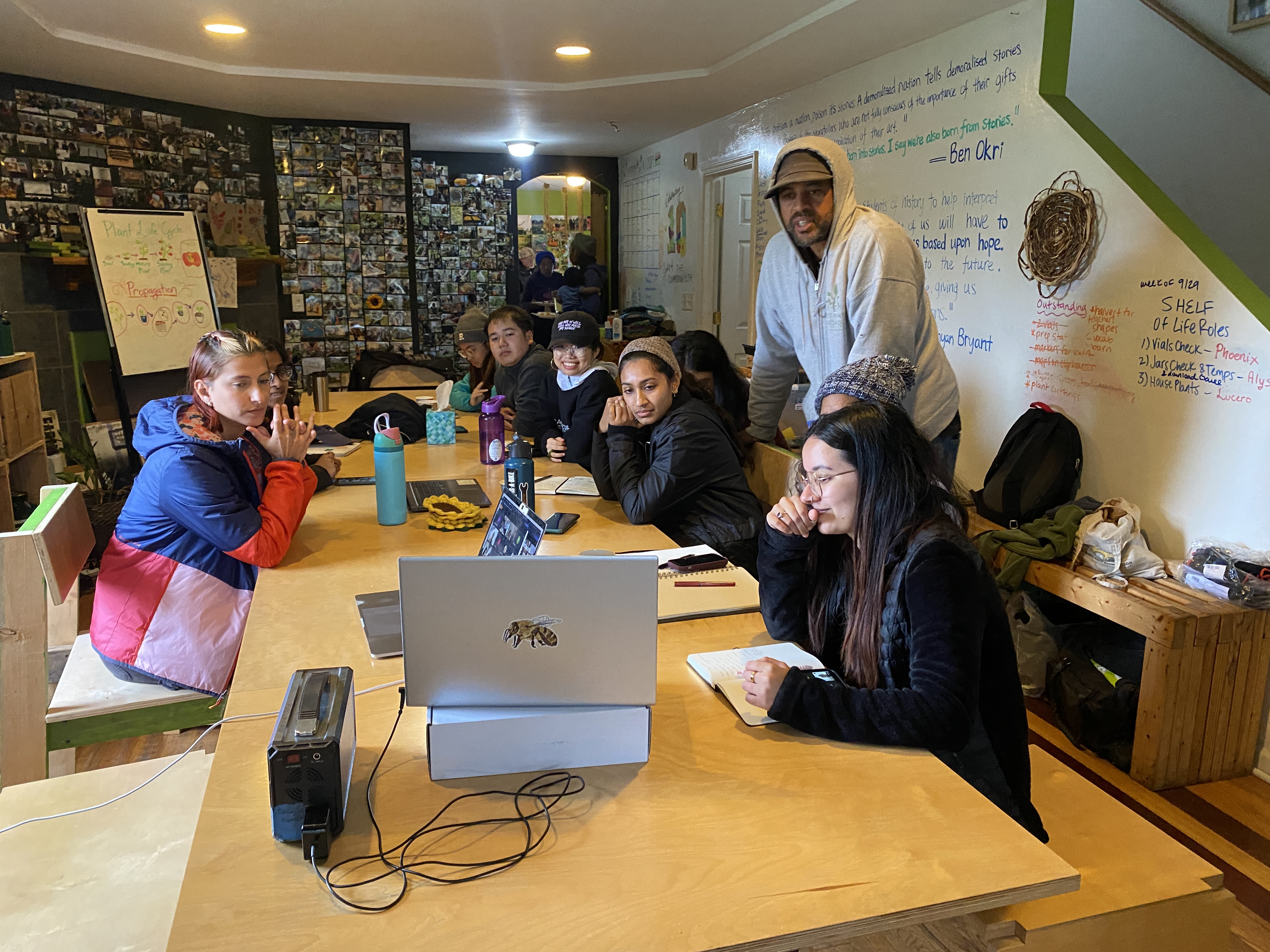 Group gathers around a table with a laptop