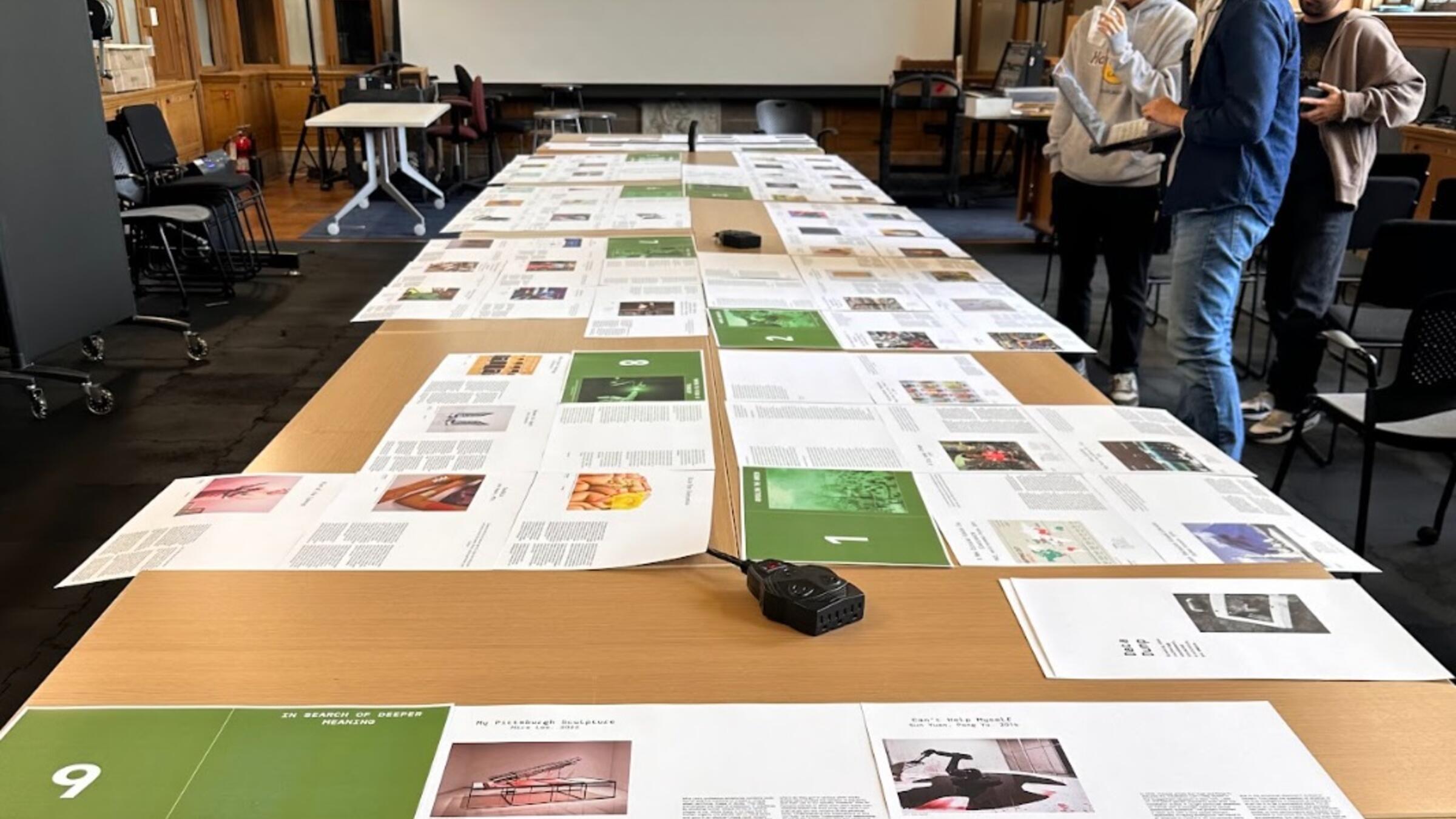 three people look at printed pages on a table