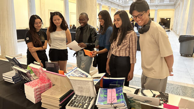 Students gather around a table with books displayed at the Pittsburgh Art Book Fair.