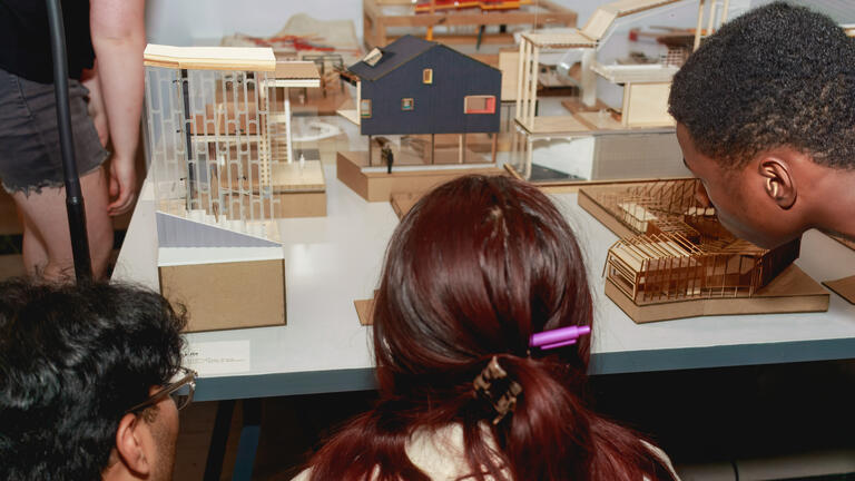 students look at models on a table at the EX-CHANGE exhibition