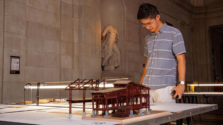 A passer-by admires student models.