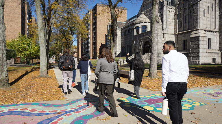 a group of people walk past buildings