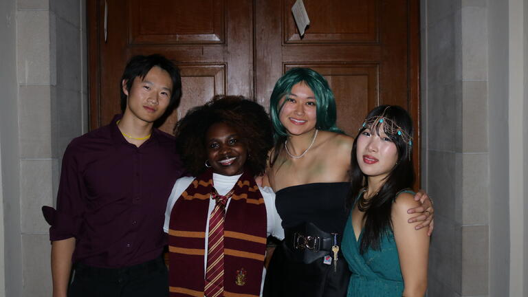 four students in costume pose for a picture