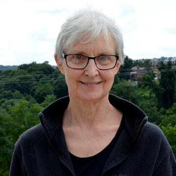 person with short hair and glasses and a black top