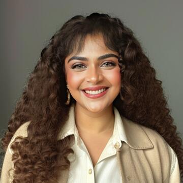 person with long brown hair, a white shirt and tan jacket on neutral background