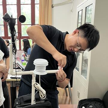 person with short hair and glasses setting up a sensor