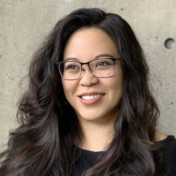 person with long brown hair and glasses wearing a black shirt