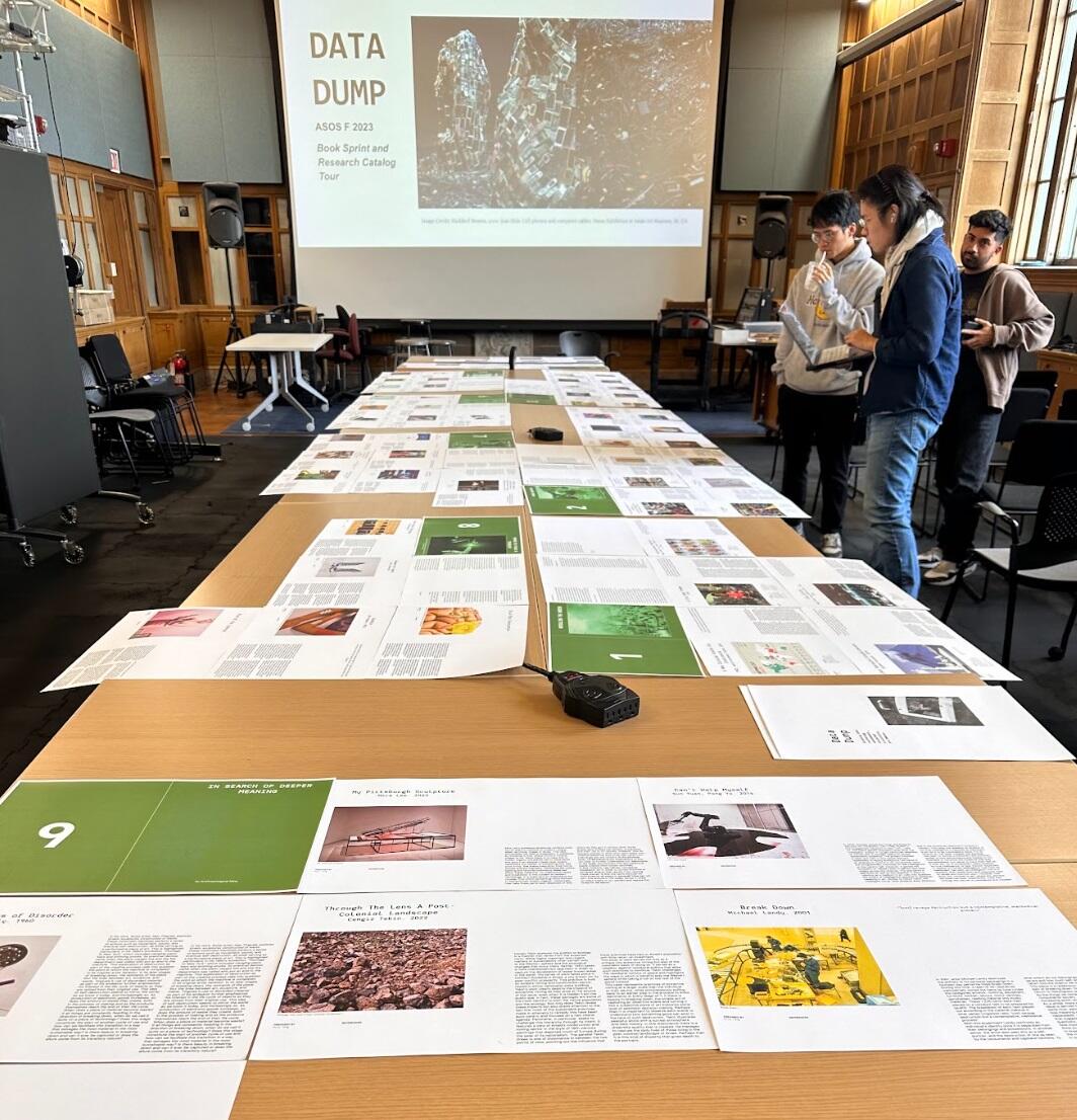 three people look at printed pages on a table