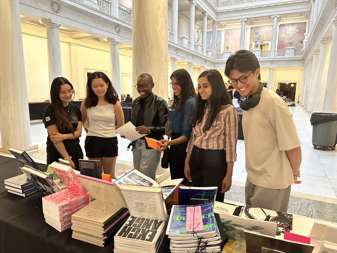 Students gather around a table with books displayed at the Pittsburgh Art Book Fair.